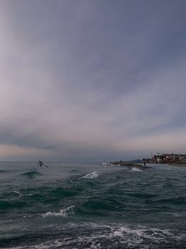 Serene ocean waves crash against a rocky coast under a cloudy sky, creating a tranquil scene.