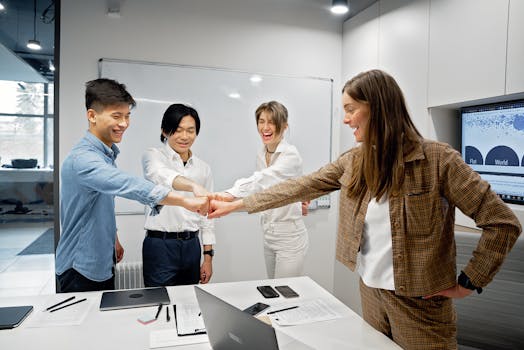 Four colleagues fist bumping in a modern office, celebrating teamwork and success.
