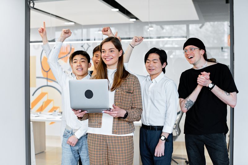 Colleagues celebrating a win around a laptop — photo by Mikhail Nilov on Pexels