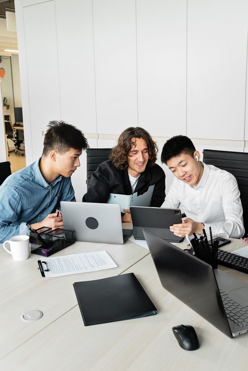 Free Three colleagues discuss ideas using technology devices in a modern office setting. Stock Photo