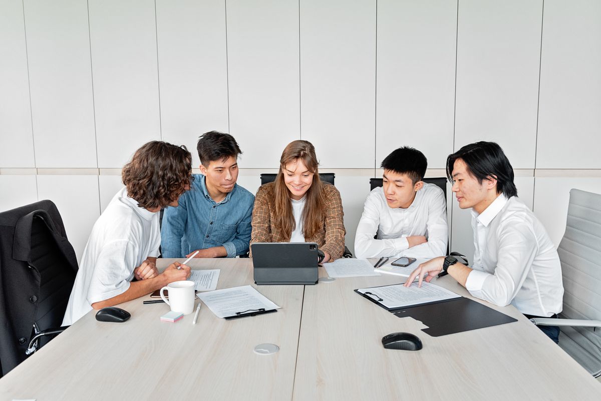 A team of advisers seated around a boardroom table reviewing documents