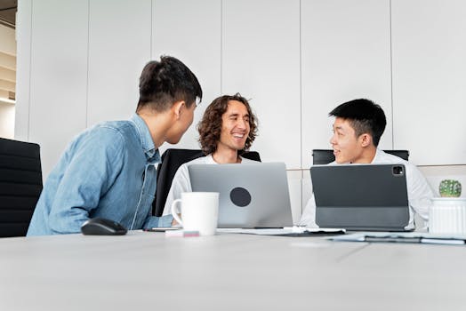 A diverse group of colleagues collaborating in a modern office with laptops and tablets.