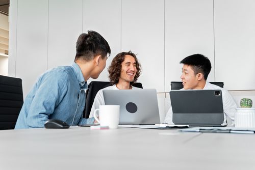 Free A diverse group of colleagues collaborating in a modern office with laptops and tablets. Stock Photo