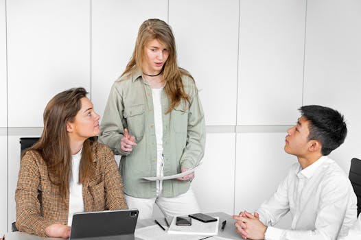 Three young professionals engaged in a collaborative discussion in a modern office environment.