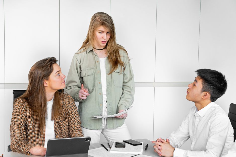 Tres jóvenes profesionales participando en una discusión colaborativa en un entorno de oficina moderno.