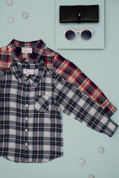 Stylish kids plaid shirts with sunglasses and wallet on blue background.