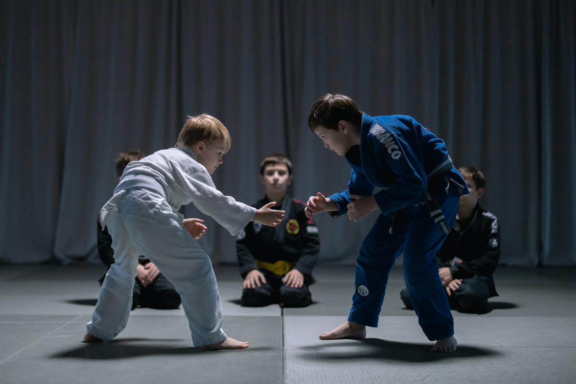 two kids wearing martial arts gi prepare to take each other down
