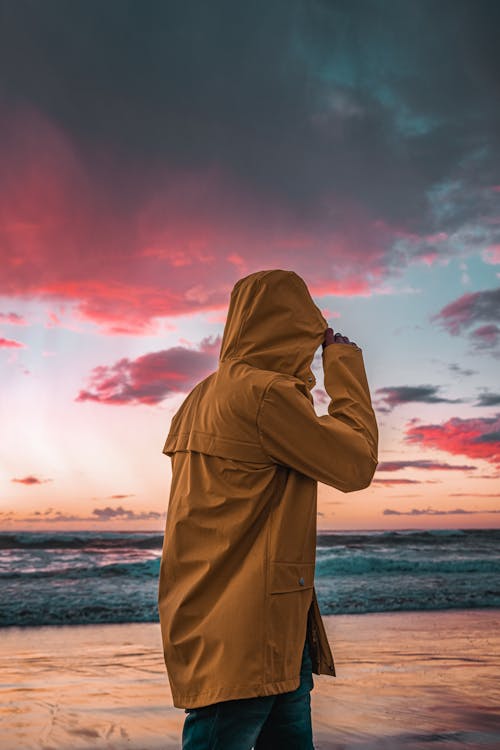 A Person Wearing a Yellow Raincoat by the Beach