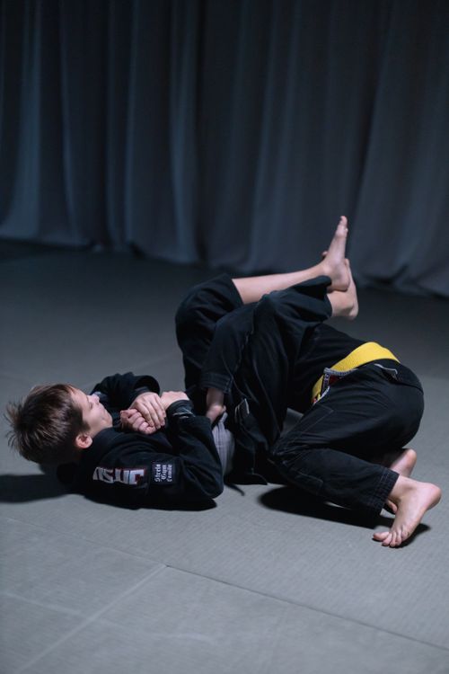 Free Two boys engaged in a jiu jitsu sparring session on an indoor mat, showcasing martial arts skills. Stock Photo