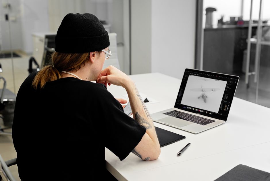 How CPAP Pillow Design Solves Mask Comfort Issues for Side Sleepers A focused designer in a beanie works on a laptop in a modern office.