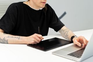 A tattooed illustrator working on a graphics tablet — photo by Mikhail Nilov on Pexels