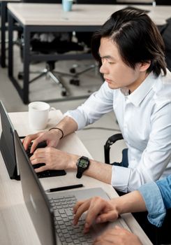 Man typing on a laptop in a modern office, focusing on work.