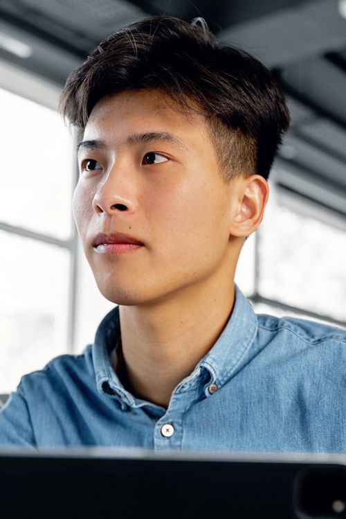 Free Confident young adult in a modern office setting, looking ahead. Stock Photo