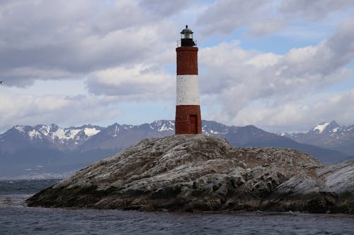 Red and White Lighthouse on Brown Rocky Mountain