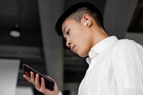 A Man Using Cellphone and a Wireless Earphone