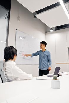 Professional man presenting graph to colleague in modern office environment.