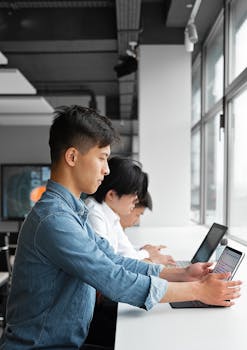 Focused group of young professionals using tablets in a modern office setting.