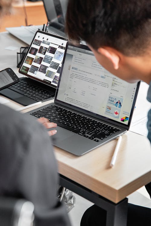 Free A Person Using a Laptop and a Tablet in a Workspace Stock Photo