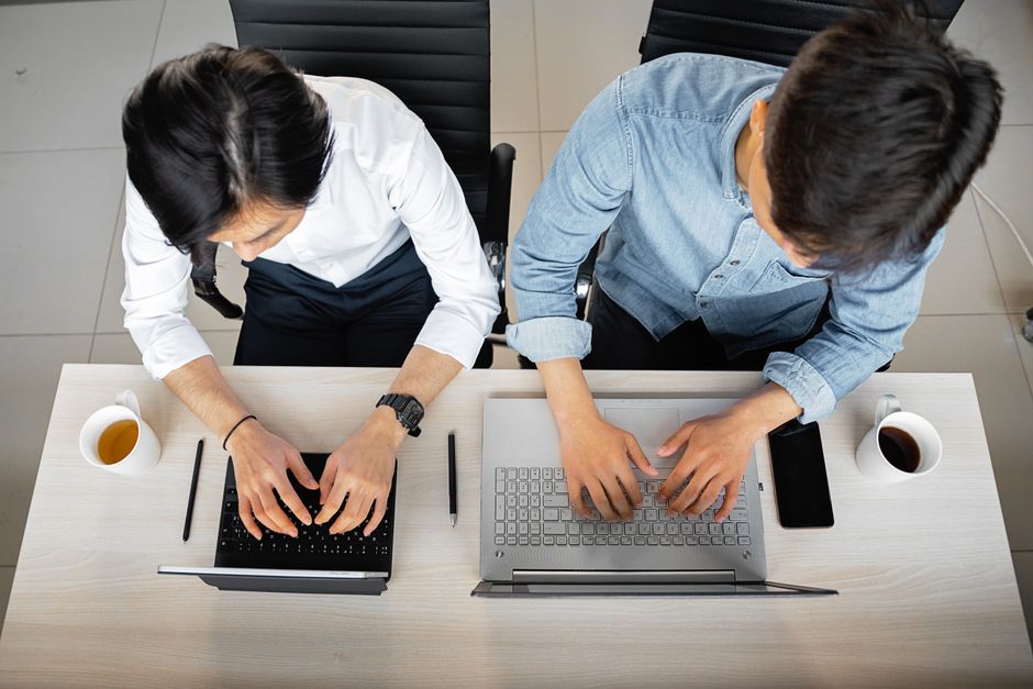 Developers working side by side on laptops — photo by Mikhail Nilov on Pexels