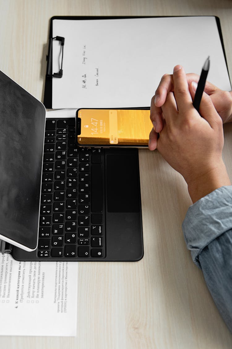 Person Using Electronics And Clipboard At Work