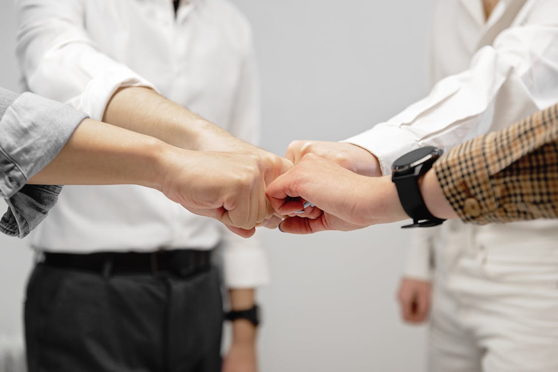 Free Close-up of diverse team members doing a fist bump indoors, symbolizing unity and teamwork. Stock Photo