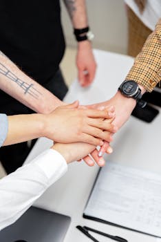 Close-up of a diverse team stacking hands on an office desk, symbolizing teamwork.