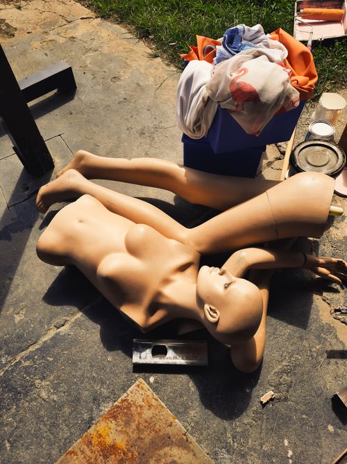 Free A broken mannequin lies on a concrete surface surrounded by debris, capturing an urban decay theme. Stock Photo