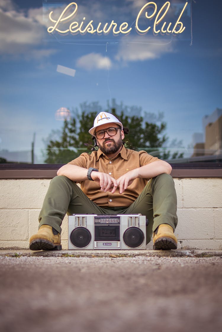 A Man Sitting On The Ground In Front Of A Radio