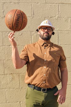 A bearded man skillfully spins a basketball in a sunny outdoor setting.
