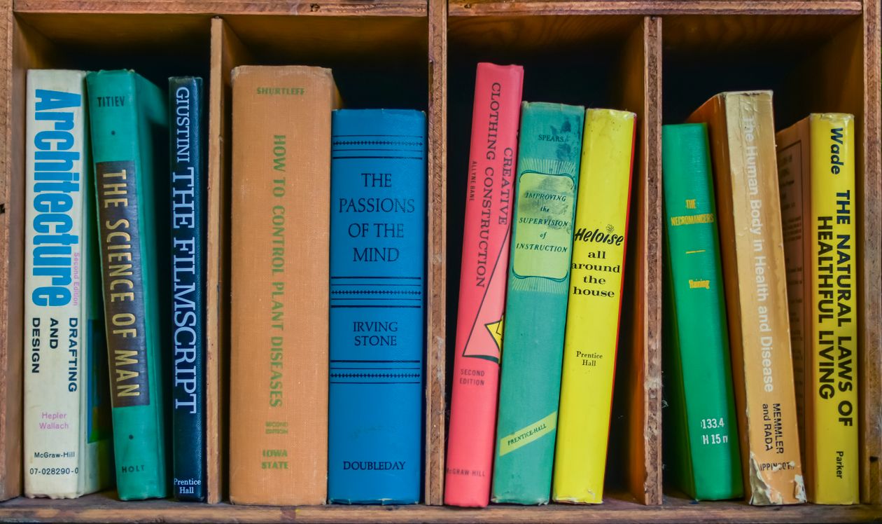 Colorful collection of books on a wooden shelf representing a must-read marketing book