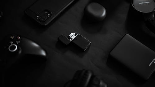 A Lighter Surrounded by Black Things on a Black Surface