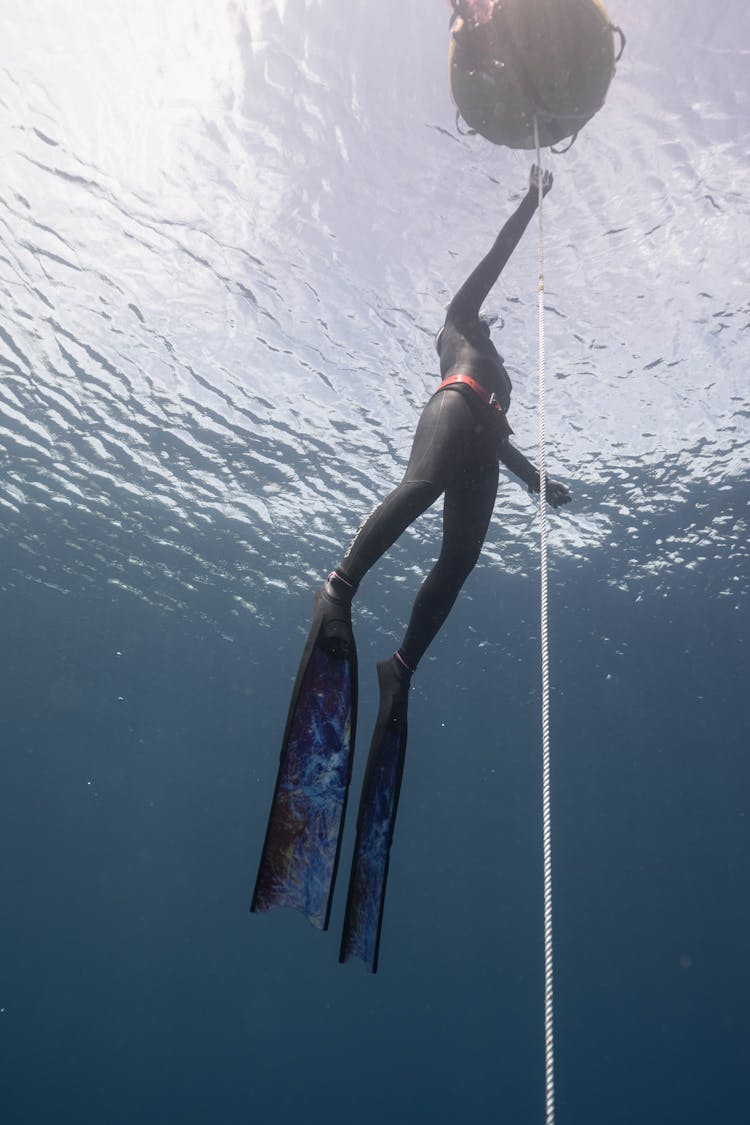 Faceless Person Swimming Underwater Near Cable