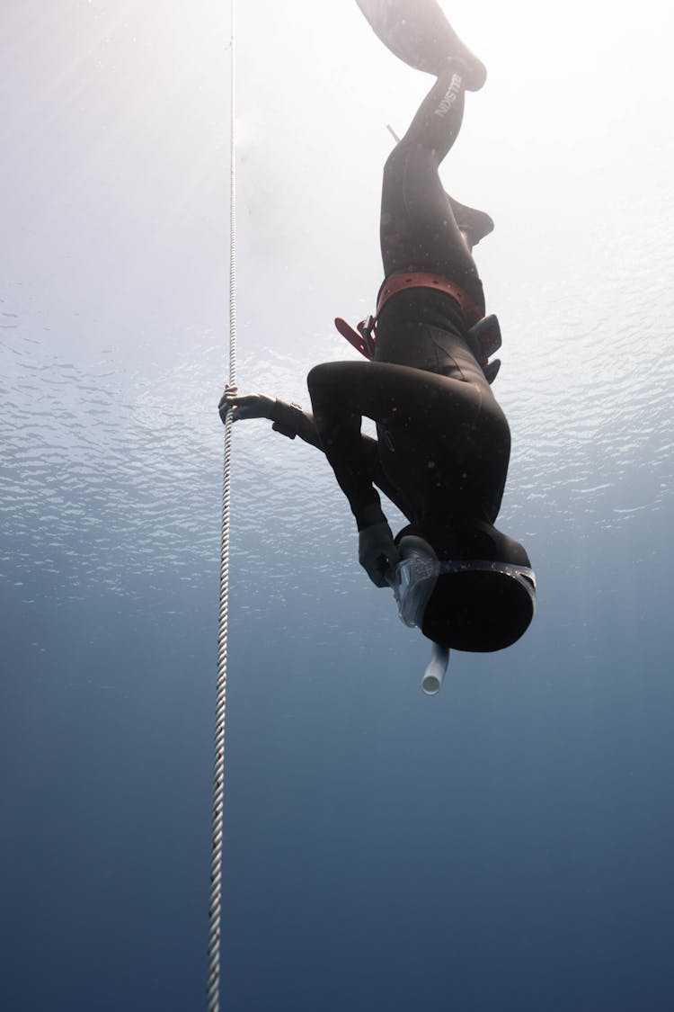 Anonymous Person Diving Underwater In Sea Near Cable