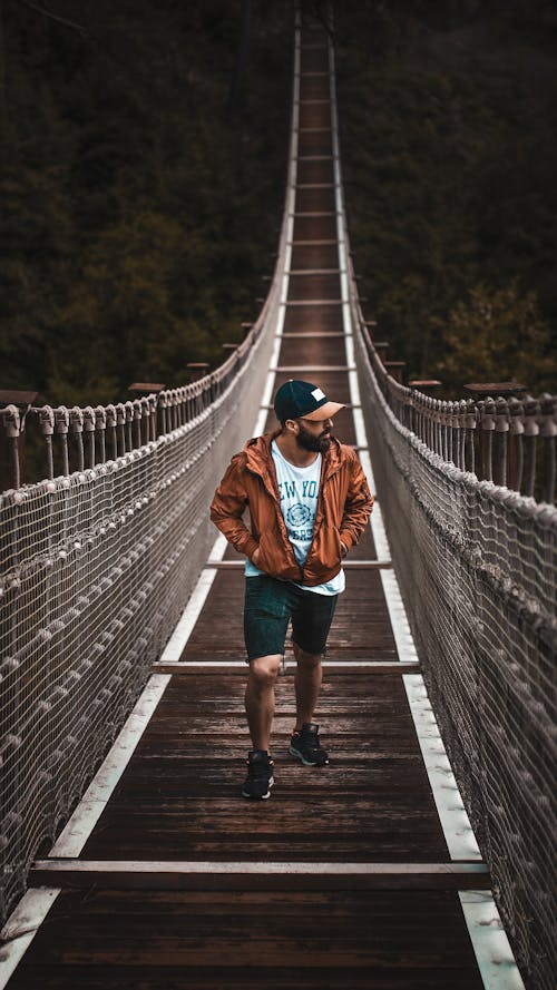 Anonymous man walking on footbridge in forest