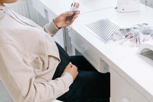 Pregnant woman browsing nail polish samples at a salon.