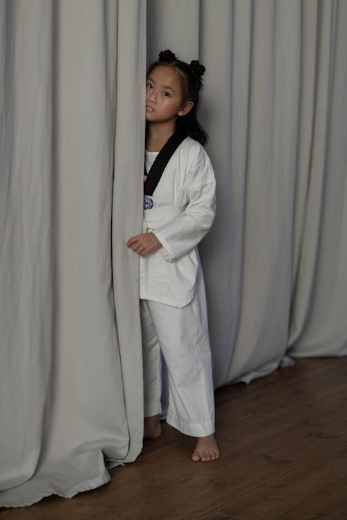 Free A Girl in Martial Arts Uniform Standing Near Curtains Stock Photo