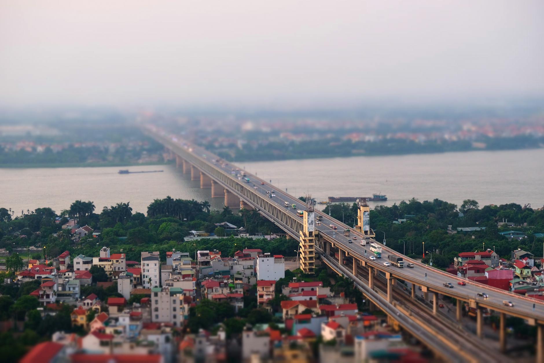 Aerial view of a bustling urban bridge with tilt-shift effect, showcasing traffic and cityscape.