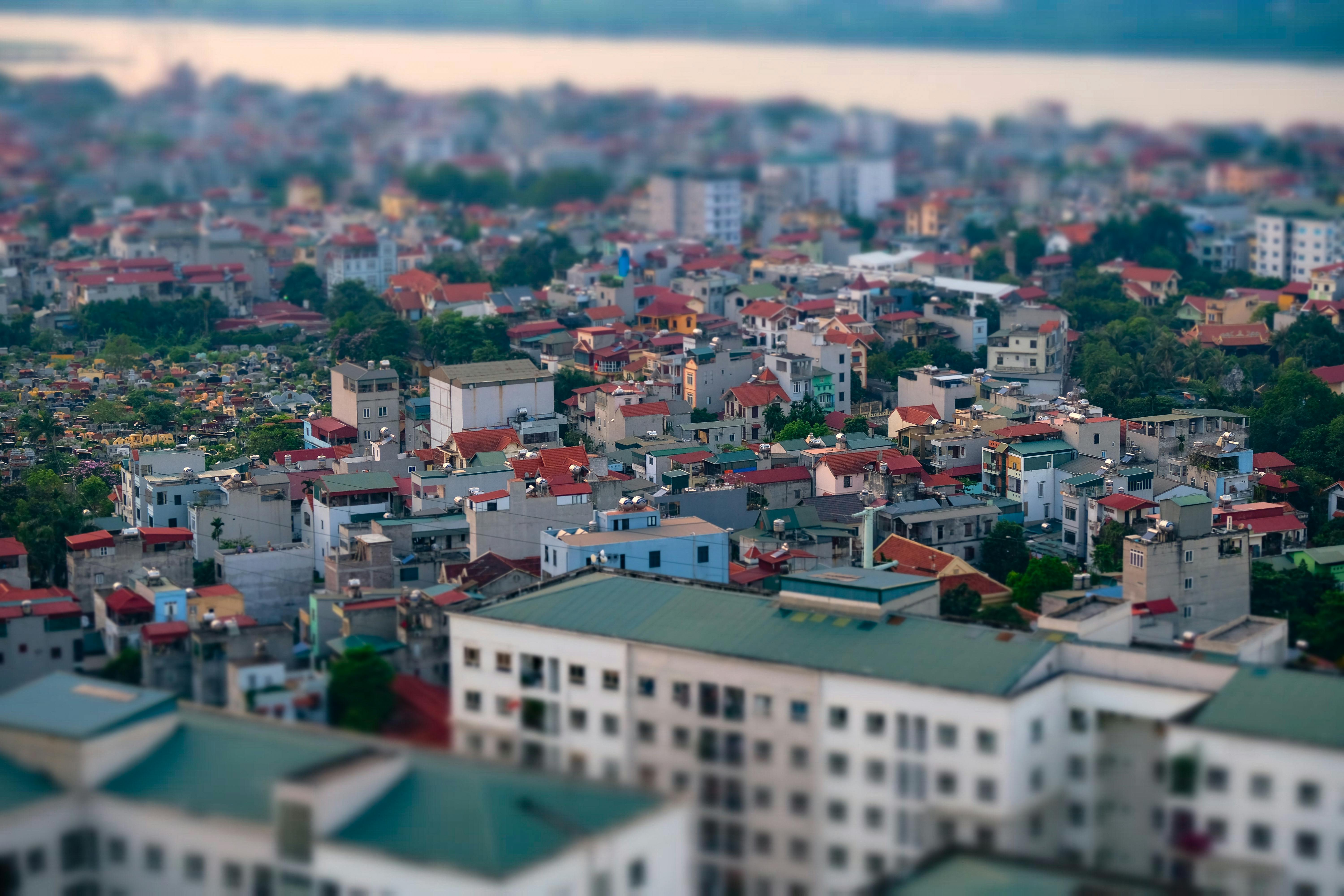 Aerial cityscape with vibrant rooftops and dense buildings captured in artistic tilt-shift style.