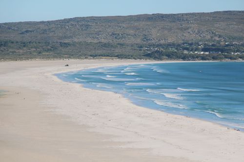 Free A picturesque beach scene capturing gentle waves lapping along the sandy shore under clear blue skies. Stock Photo