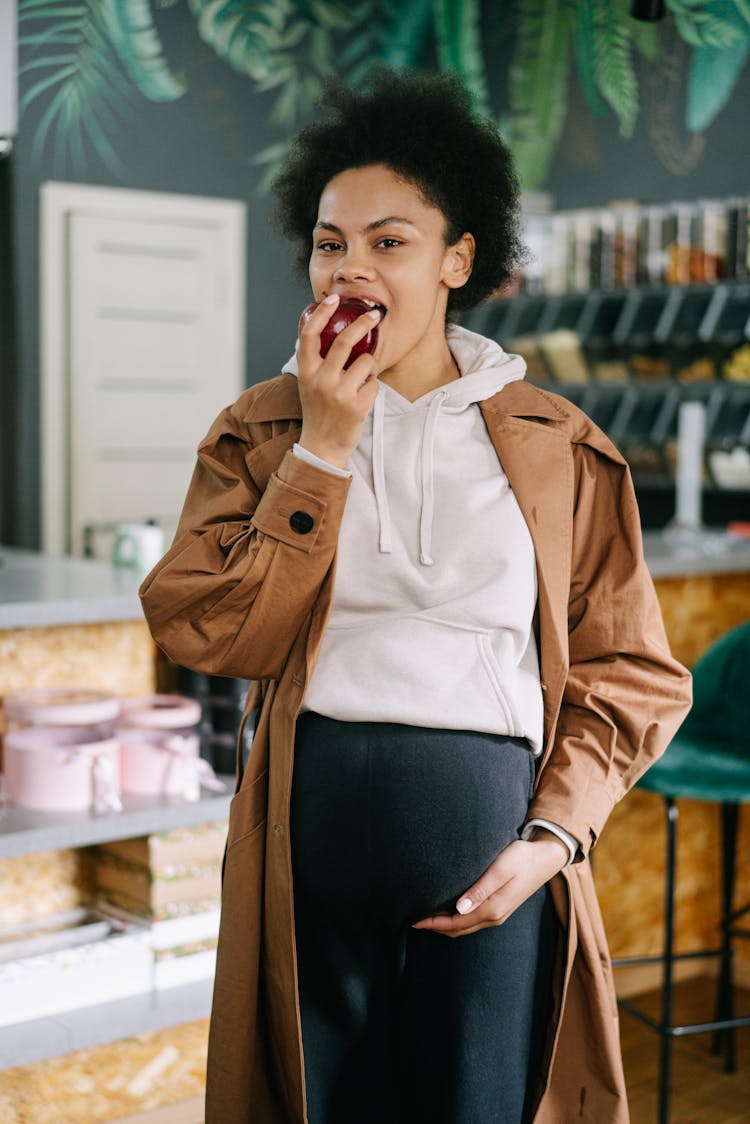 A Pregnant Woman Eating An Apple