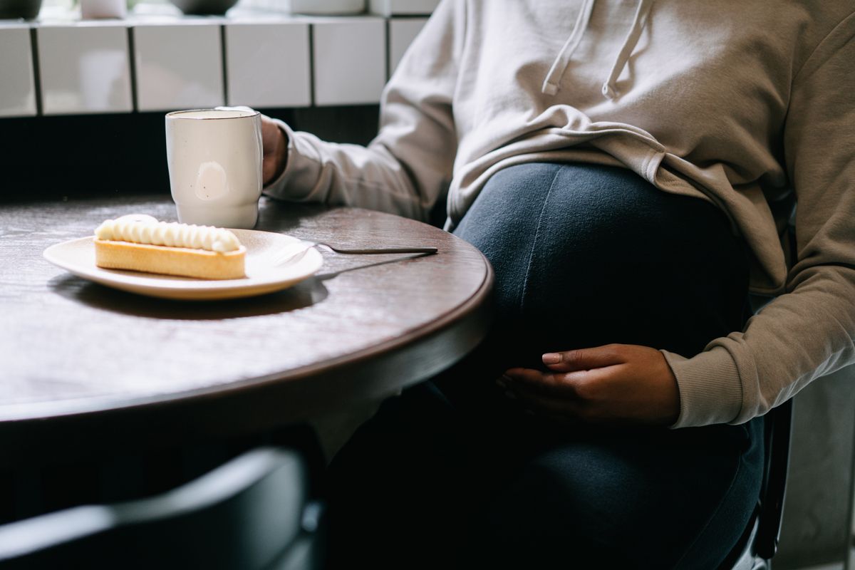 Pregnant woman holding a drink at the table