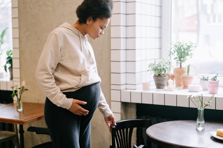 A Pregnant Woman Wearing Hoodie Jacket Pulling A Chair