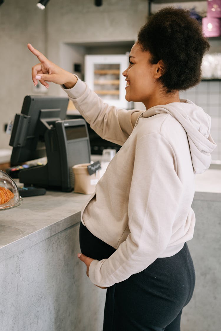 A Pregnant Woman Holding Her Baby Bump While Pointing A Finger