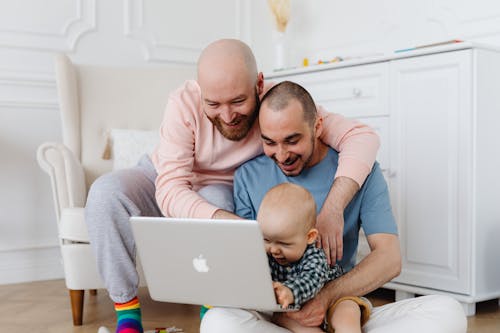 Free Two Men Hugging and Holding Baby Boy While Looking at the Laptop
 Stock Photo