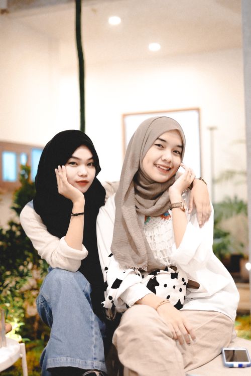 Free Two friends enjoy a moment together indoors, wearing hijabs and sharing smiles. Stock Photo