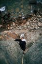 Man in Black Jacket and White Helmet Sitting on Rocky Ground