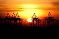 汉堡港上空的日落令人惊叹，起重机的轮廓捕捉到了工业之美