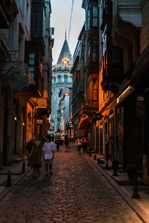 People Walking on Narrow Street Between Buildings of Old Town