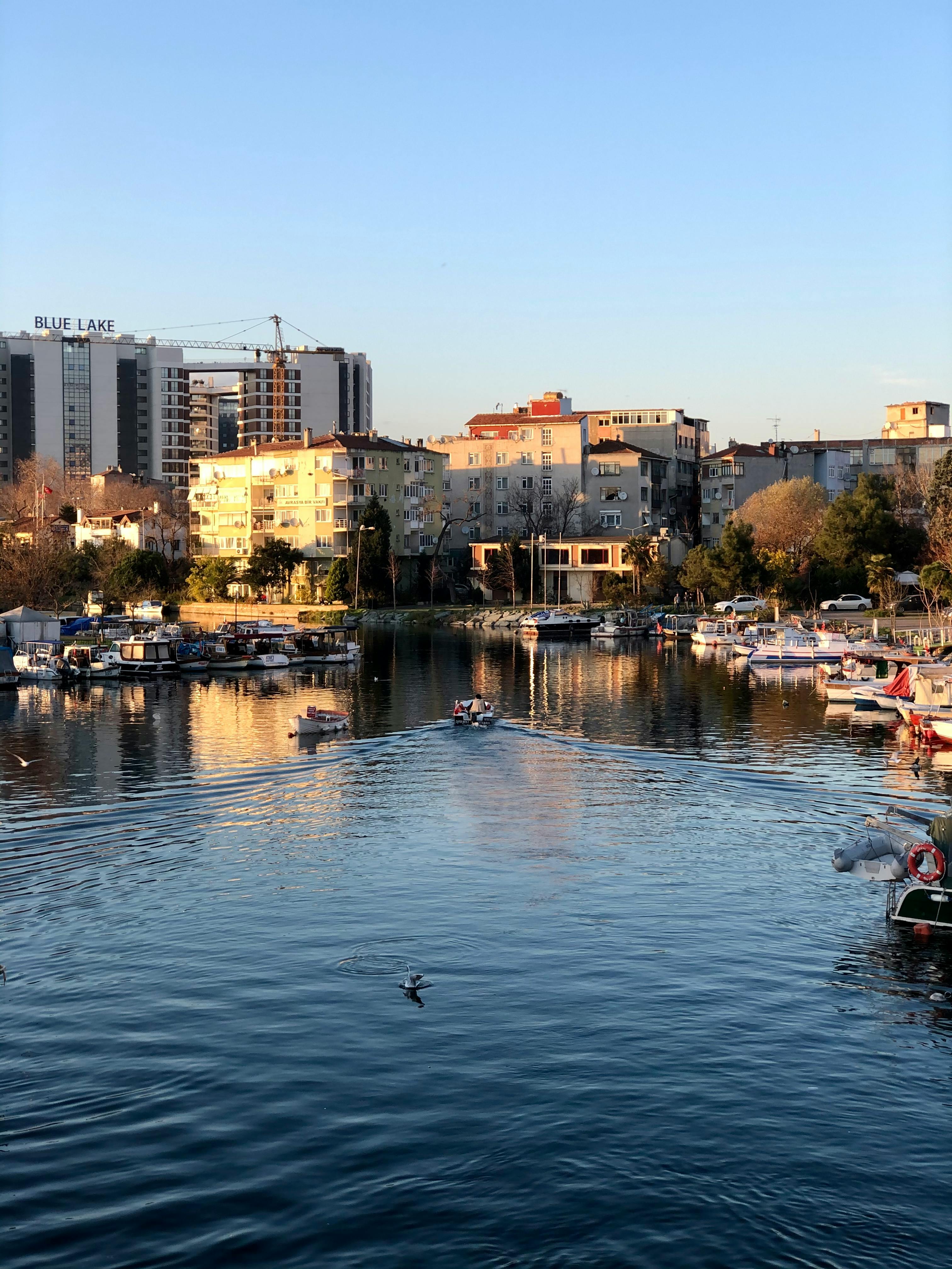Scenic view of İstanbul marina with boats and urban buildings at sunset.