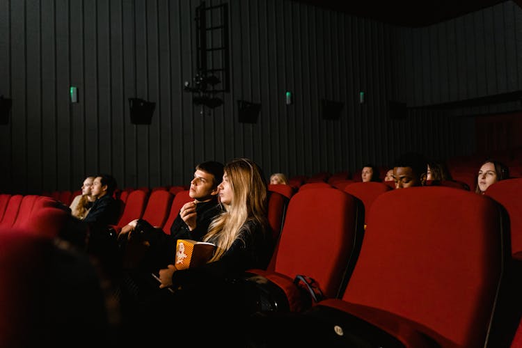 A Couple Eating Popcorn While Watching A Movie